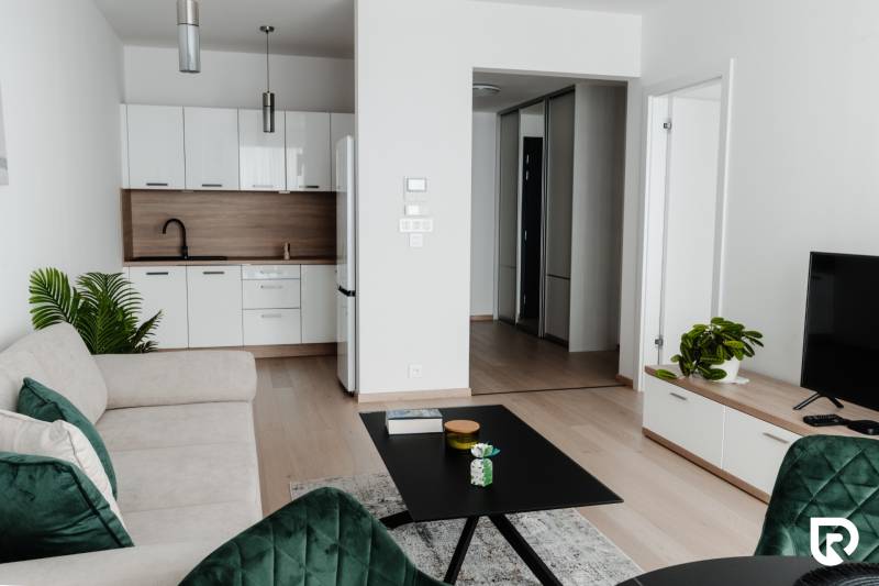 | E2Tower | 20.poschodie | 2i byt | panoramatický výhľad |  - Obývačka v 2-izbovom byte so sedačkou, kuchyňou a podlahou s dreveným dekorom.