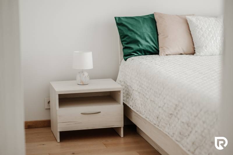 | E2Tower | 20.poschodie | 2i byt | panoramatický výhľad |  - Nočný stolík s lampou pri posteli, 2-izbový byt, podlaha s dreveným dekorom.