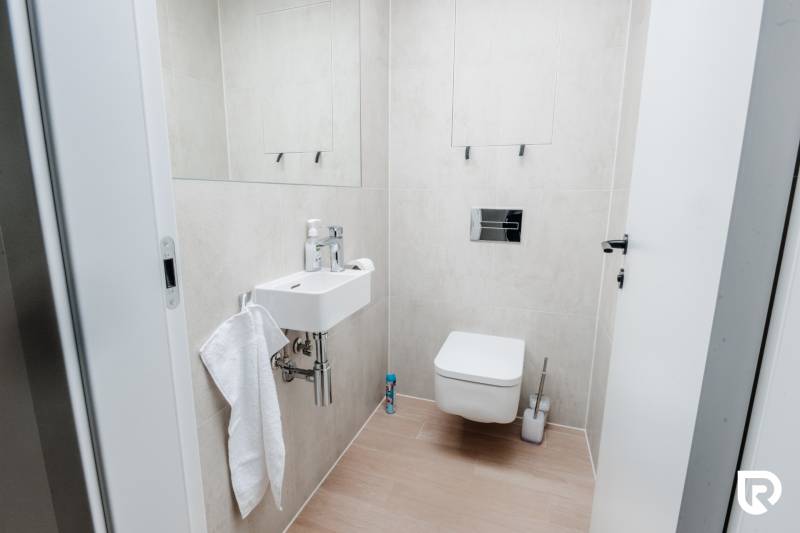 | E2Tower | 20.poschodie | 2i byt | panoramatický výhľad |  - Kúpeľňa 2-izbového bytu s toaletou, umývadlom a podlahou s dreveným dekorom.