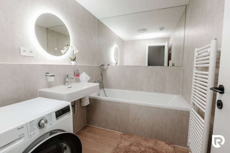 | E2Tower | 20.poschodie | 2i byt | panoramatický výhľad |  - Kúpeľňa v 2-izbovom byte s umývadlom, vaňou a práčkou, dlažba s dreveným dekorom.