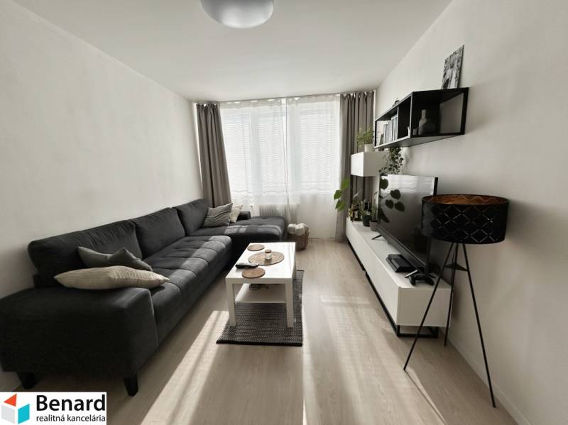 NA PREDAJ ŠTÝLOVÝ 2- IZBOVÝ BYT, 50m2, SÍDLISKO 2, PREŠOV - Obývacia izba s pohovkou, televízorom a podlahou s dreveným dekorom v 2-izbovom byte.