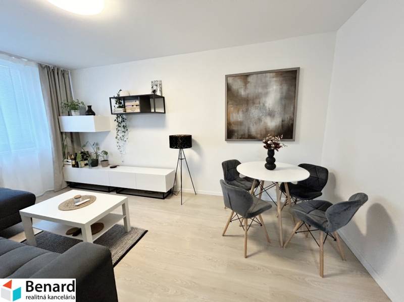 NA PREDAJ ŠTÝLOVÝ 2- IZBOVÝ BYT, 50m2, SÍDLISKO 2, PREŠOV - Interiér 2-izbového bytu so stolom, stoličkami a dekoráciami, podlaha s dreveným dekorom.