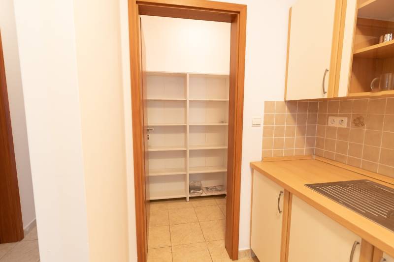 Luxusný 2-izbový byt + 2 balkóny, 73 m², garážové státie, Ružinov - Kuchyňa v 2-izbovom byte s poličkami a dlažbou, skrinky s dreveným dekorom.