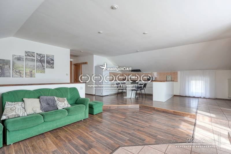 4-izbový podkrovný byt s nebytovým priestorom v obci Pavlice - Interiér rodinného domu s pohovkou, kuchynským kútom a podlahou s dreveným dekorom.