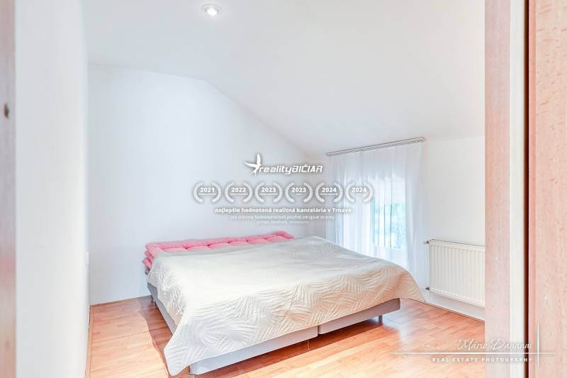 4-izbový podkrovný byt s nebytovým priestorom v obci Pavlice - Spálňa v rodinnom dome s veľkou posteľou a podlahou s dreveným dekorom.