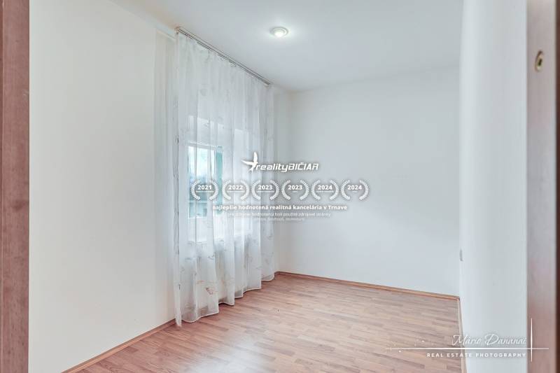 4-izbový podkrovný byt s nebytovým priestorom v obci Pavlice - Svetlá miestnosť s podlahou s dreveným dekorom a záclonami v rodinnom dome.