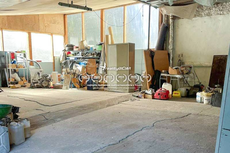 4-izbový podkrovný byt s nebytovým priestorom v obci Pavlice - Garáž v rodinnom dome plná nástrojov a strojov, s rôznym vybavením na policiach.
