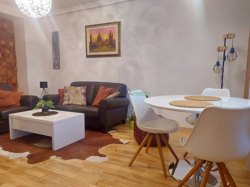 Vkusný, moderný 2 izb, klíma, 870 s ener., Sibírska ul./Nové Mesto - Interiér 2-izbového bytu s podlahou s dreveným dekorom, koženými sedačkami a okrúhlym stolom.