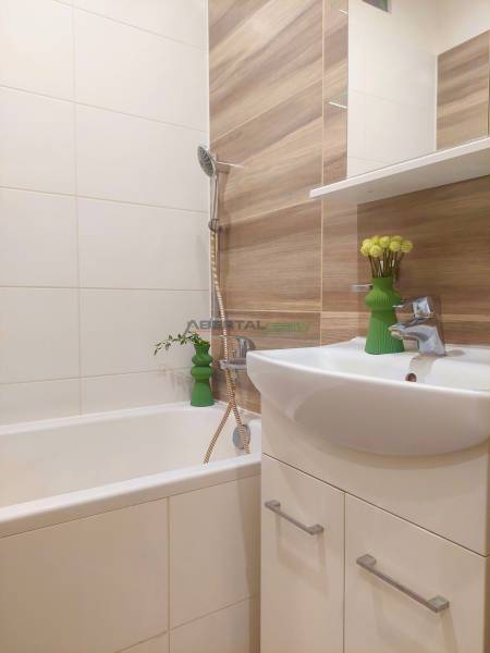 Vkusný, moderný 2 izb, klíma, 870 s ener., Sibírska ul./Nové Mesto - Kúpeľňa v 2-izbovom byte s vaňou a umývadlom, obkladaná dlaždicami s dreveným dekorom.