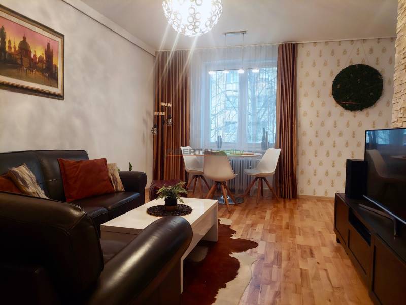 Vkusný, moderný 2 izb, klíma, 870 s ener., Sibírska ul./Nové Mesto - Obývačka s koženou sedačkou, jedálenským stolom a podlahou s dreveným dekorom v 2-izbovom byte.