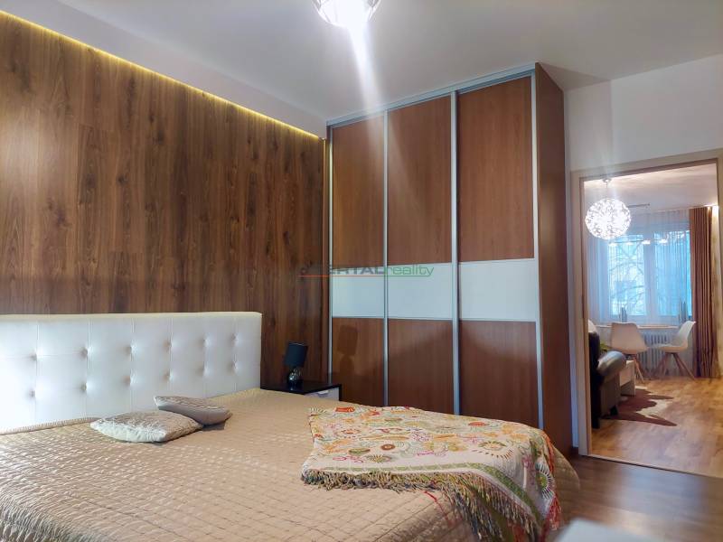 Vkusný, moderný 2 izb, klíma, 870 s ener., Sibírska ul./Nové Mesto - Spálňa s podlahou s dreveným dekorom, posuvnými skriňami a prechodom do obývačky v 2-izbovom byte.