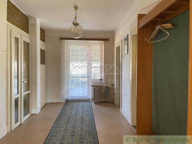 Vidiecky dom v gemerskej obci Bretka - Interiér rodinného domu s podlahou s dreveným dekorom, závesom a kobercom.