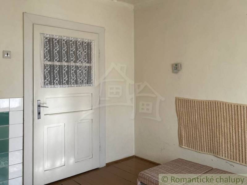 Vidiecky dom v gemerskej obci Bretka - Interiér rodinného domu s bielymi dverami, obkladom a podlahou s dreveným dekorom.