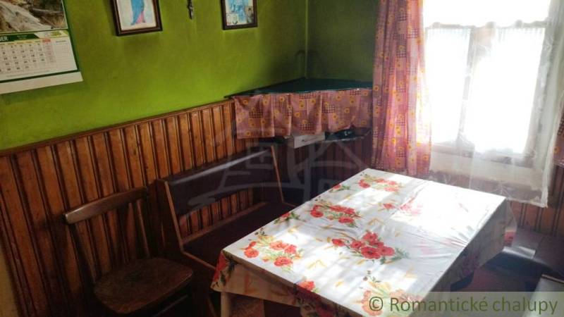 Pôvodná goralská drevenica, Osturňa - Izba v rodinnom dome s dreveným obložením, kvetinovým obrusom a záclonami.