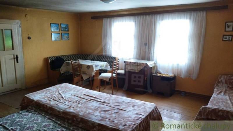 Pôvodná goralská drevenica, Osturňa - Útulná izba s dreveným dekorom, oknami, stolom a posteľou v rodinnom dome.