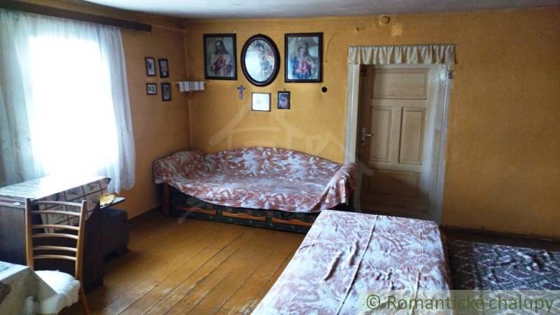 Pôvodná goralská drevenica, Osturňa - Interiér rodinného domu s drevenou podlahou, stoly, stoličky, nástenné dekorácie.