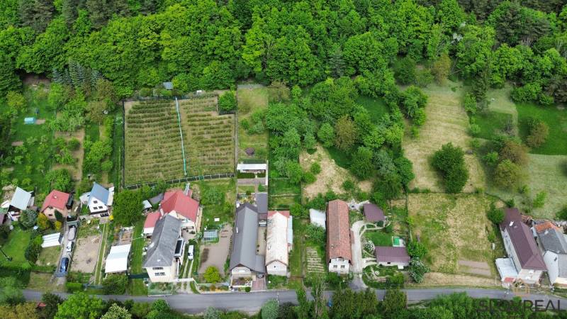 Predaj domu v Janovej Lehote - Rodinné domy obklopené zeleňou v Janovej Lehote, záhrady a lesy v pozadí.