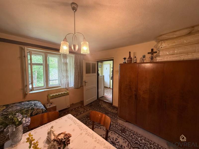 Predaj domu v Janovej Lehote - Interiér rodinného domu s jedálenským stolom, skriňou a otvoreným oknom.