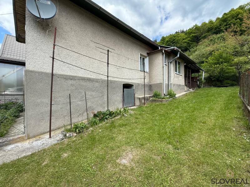 Predaj domu v Janovej Lehote - Rodinný dom v Janovej Lehote obklopený záhradou, so satelitnou anténou na fasáde.