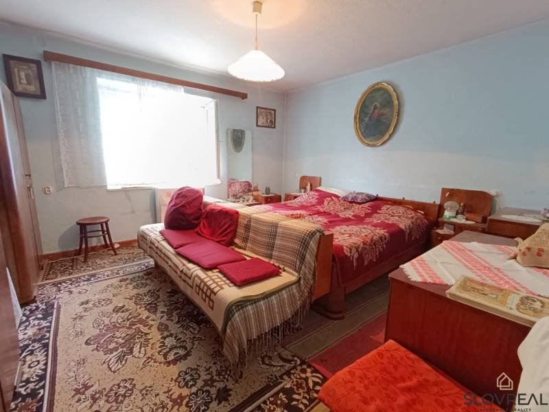 Predaj domu v Janovej Lehote - Izba v rodinnom dome s posteľou, sedačkou a dekoratívnym kobercom.