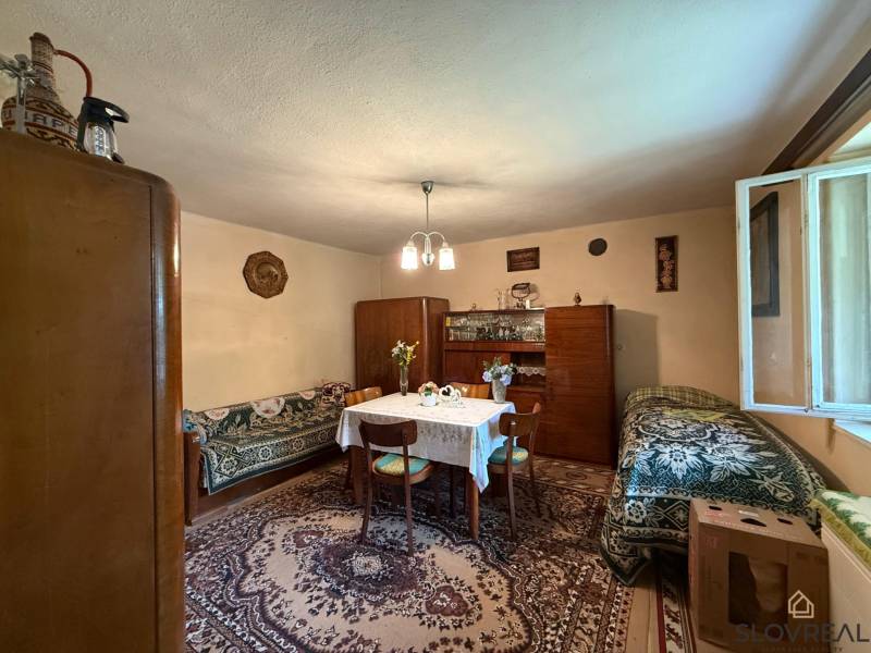 Predaj domu v Janovej Lehote - Obývacia izba s kobercom, dreveným nábytkom a stolom v rodinnom dome.