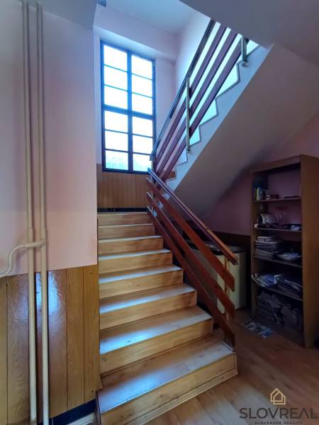 : Predaj rodinného domu s veľkým pozemkom v obci Pitelová  - Podlaha s dreveným dekorom a schodisko s oknom v Rodinnom dome.