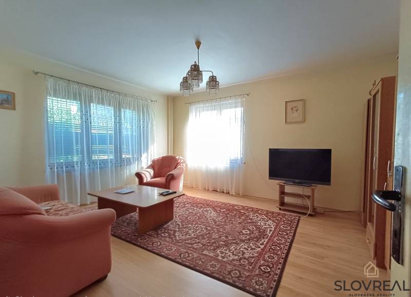 : Predaj rodinného domu s veľkým pozemkom v obci Pitelová  - Obývacia izba v rodinnom dome s pohovkou, televízorom a podlahou s dreveným dekorom.