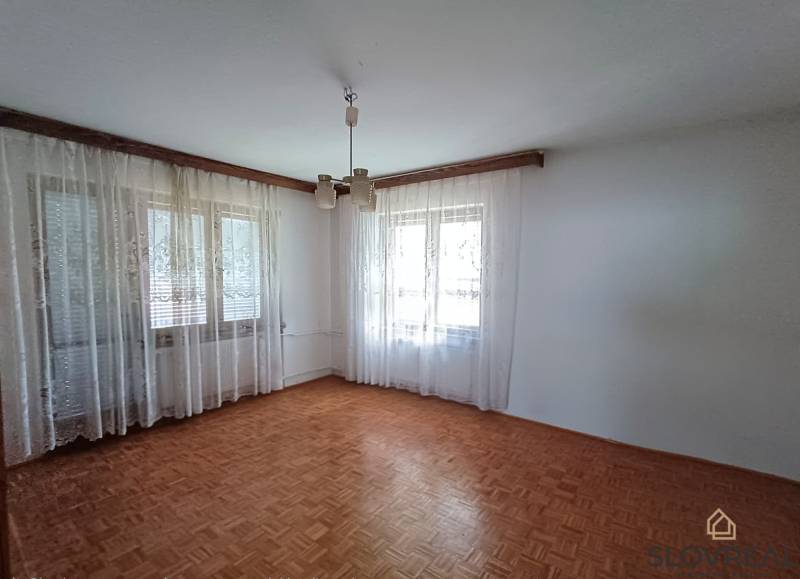 : Predaj rodinného domu s veľkým pozemkom v obci Pitelová  - Svetlá izba s bielymi závesmi a podlahou s dreveným dekorom v rodinnom dome.