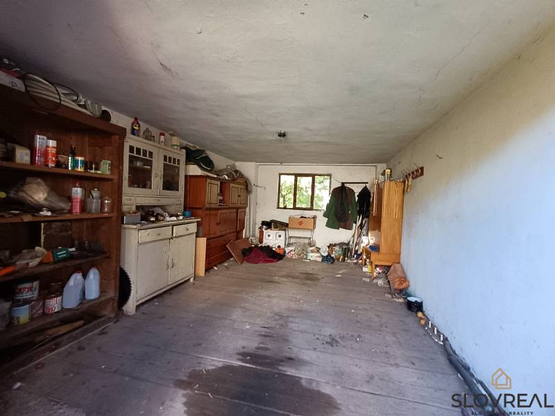 : Predaj rodinného domu s veľkým pozemkom v obci Pitelová  - Pivnica v rodinnom dome s policami, starým nábytkom a rôznymi predmetmi.
