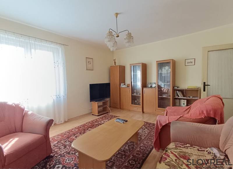 : Predaj rodinného domu s veľkým pozemkom v obci Pitelová  - Obývacia izba s dreveným dekorom, pohovkou, televízorom a vitrínami v Rodinnom dome.