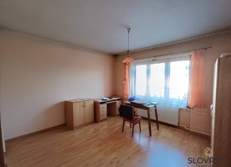 : Predaj rodinného domu s veľkým pozemkom v obci Pitelová  - Interiér rodinného domu s nábytkom a podlahou s dreveným dekorom, stolička pri stole.