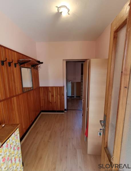 : Predaj rodinného domu s veľkým pozemkom v obci Pitelová  - Interiér rodinného domu s podlahou s dreveným dekorom a drevenými obkladmi na stenách.