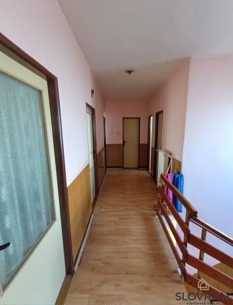 : Predaj rodinného domu s veľkým pozemkom v obci Pitelová  - Chodba v rodinnom dome s podlahou s dreveným dekorom a dreveným zábradlím.