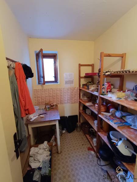 : Predaj rodinného domu s veľkým pozemkom v obci Pitelová  - Špajza v rodinnom dome s policami a oknom, rôzne uskladnené predmety a potraviny.