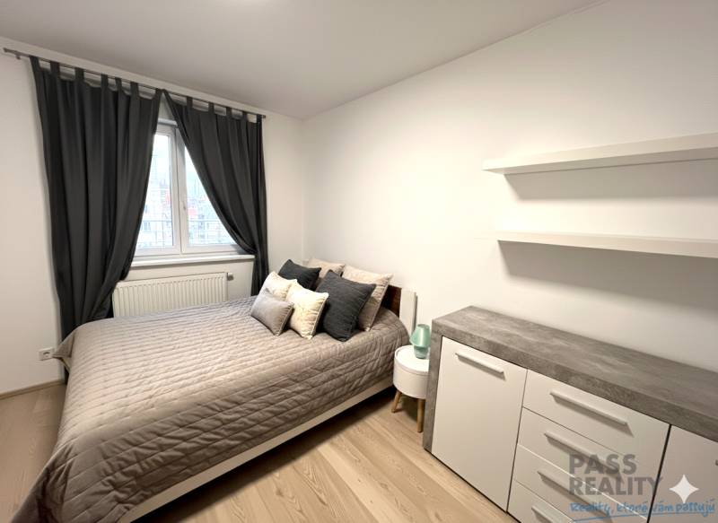 REZERVOVANÉ-PREDAJ 2 izbový byt s garážou v skvelej lokalite v Ružinov - Spálňa v 2-izbovom byte s posteľou, komodou a závesmi, podlaha s dreveným dekorom.