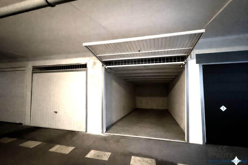 REZERVOVANÉ-PREDAJ 2 izbový byt s garážou v skvelej lokalite v Ružinov - Otvorená garáž s prázdnym interiérom a bielymi stenami.