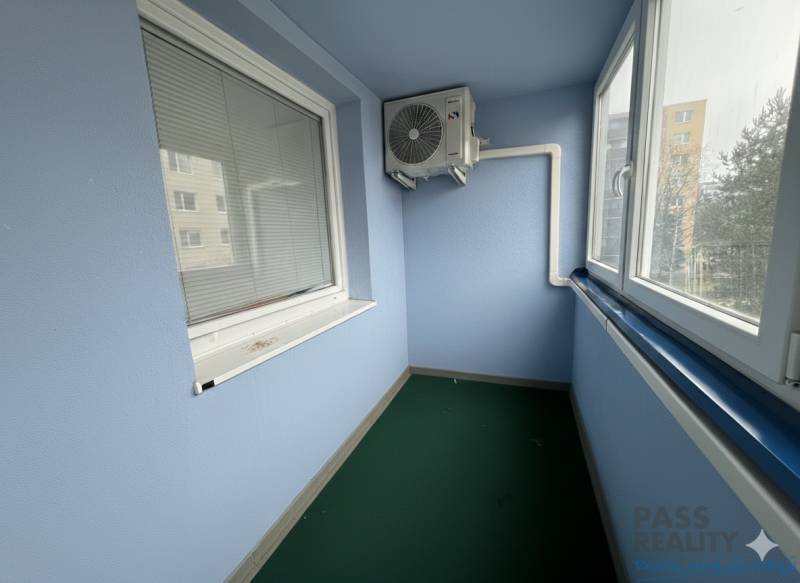 REZERVOVANÉ-PREDAJ 2 izbový byt s garážou v skvelej lokalite v Ružinov - Zasklená lodžia s klimatizačnou jednotkou v 2-izbovom byte, vybavená žalúziami a zeleným kobercom.