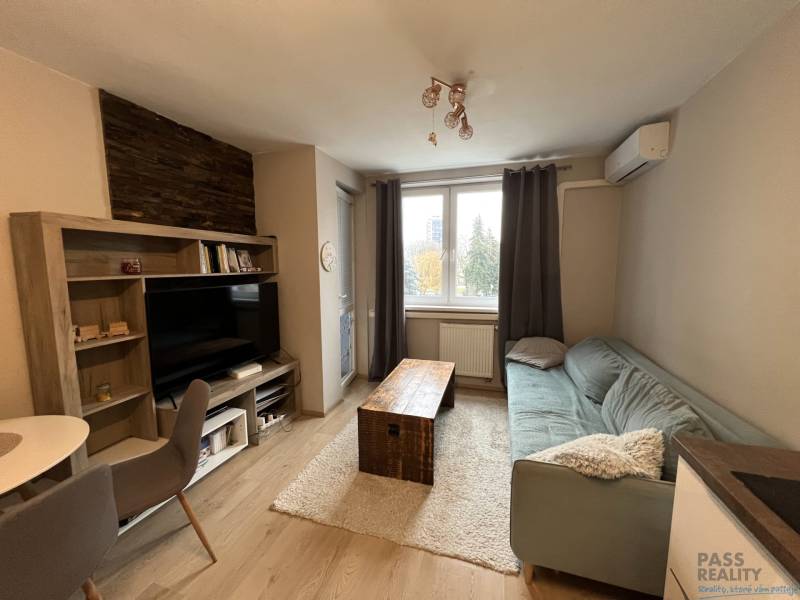 REZERVOVANÉ-PREDAJ 2 izbový byt s garážou v skvelej lokalite v Ružinov - Obývacia izba s podlahou s dreveným dekorom, pohovkou a televízorom v 2-izbovom byte.