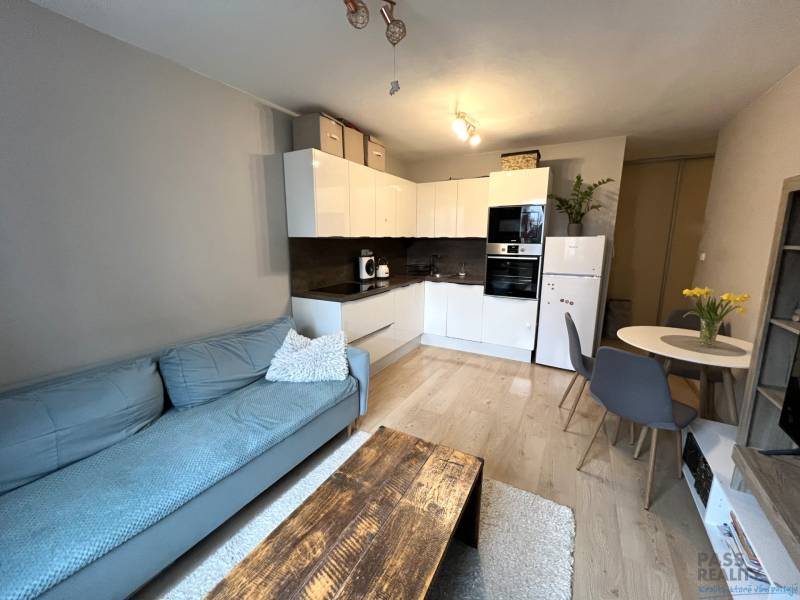 REZERVOVANÉ-PREDAJ 2 izbový byt s garážou v skvelej lokalite v Ružinov - Obývacia časť 2-izbového bytu s kuchyňou, sedačkou a jedálenským stolom.