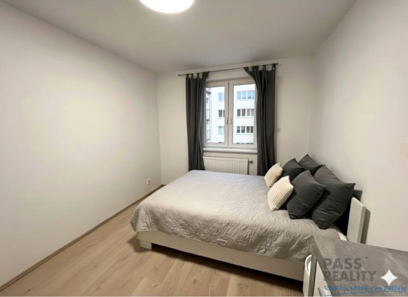 REZERVOVANÉ-PREDAJ 2 izbový byt s garážou v skvelej lokalite v Ružinov - Spálňa s posteľou a podlahou s dreveným dekorom v 2-izbovom byte.