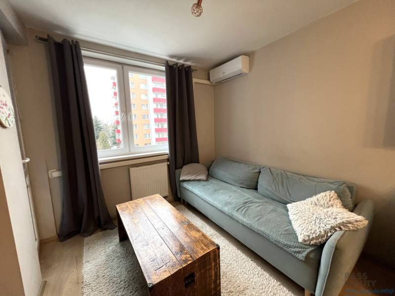 REZERVOVANÉ-PREDAJ 2 izbový byt s garážou v skvelej lokalite v Ružinov - Obývacia izba v 2-izbovom byte s podlahou s dreveným dekorom a pohovkou.