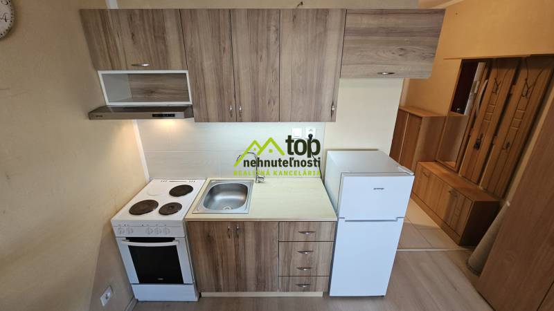 TOPOĽĆANY - zariadená garsónka na sídlisku JUH - Kuchyňa v garsónke s podlahou s dreveným dekorom a základným vybavením.
