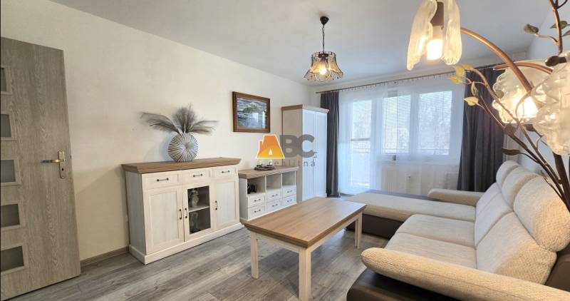 Moderný 2-izbový byt po rekonštrukcii v srdci Zlatého potoka - Zvolen - Obývacia izba v 2-izbovom byte s podlahou s dreveným dekorom, sedačkou a bielym nábytkom.