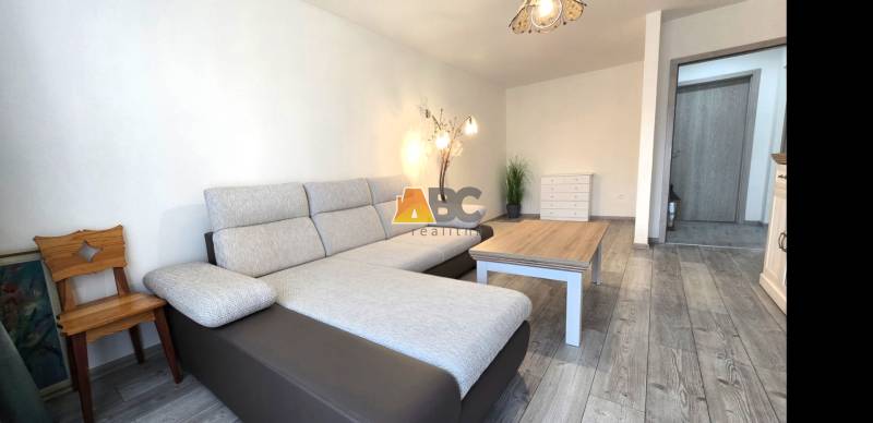 Moderný 2-izbový byt po rekonštrukcii v srdci Zlatého potoka - Zvolen - Obývačka s pohovkou a podlahou s dreveným dekorom v 2-izbovom byte.