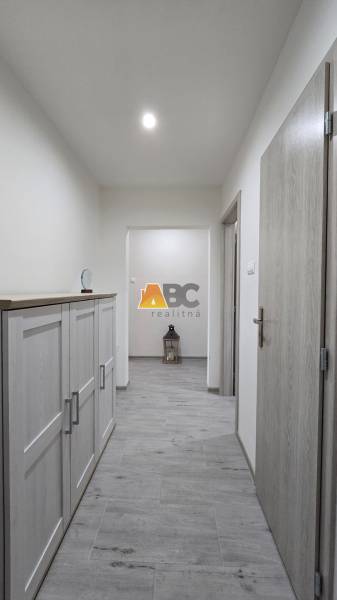 Moderný 2-izbový byt po rekonštrukcii v srdci Zlatého potoka - Zvolen - Chodba s podlahou s dreveným dekorom v 2-izbovom byte, nábytok na ľavej strane.