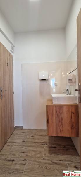 Prenájom kaviarne  v obci Nová Dedinka pri Senci - Interiér gastro priestoru so svetlými stenami, podlahou s dreveným dekorom a umývadlom.