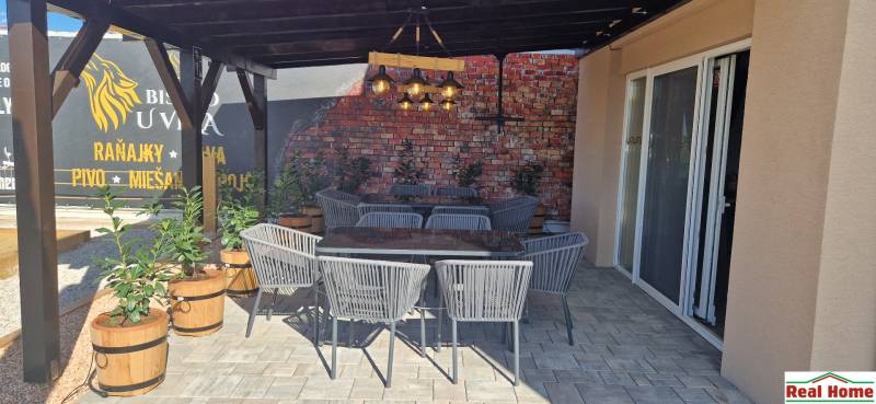 Prenájom kaviarne  v obci Nová Dedinka pri Senci - V exteriérových gastro priestoroch v Novej Dedinke sú ratanové stoličky a tehlová stena.