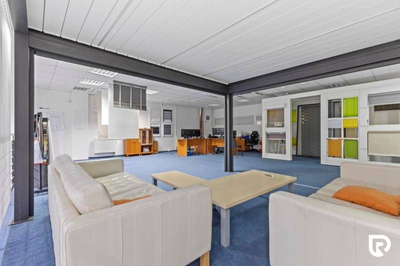 Kancelárie-Showroom 357 m², Zadunajská cesta, Petržalka, BA - Interiér obchodných priestorov s krémovou sedačkou, modrým kobercom a stolmi.