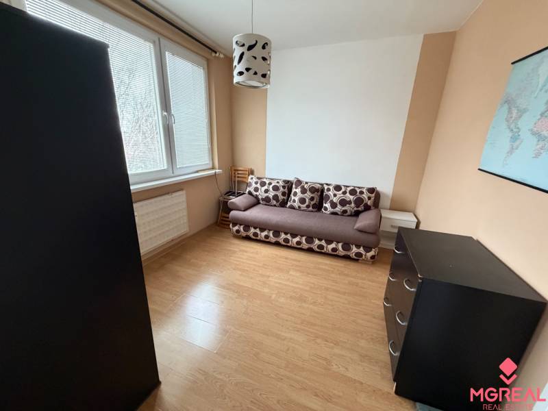 3 izbový byt bez balkóna Topoľčany  - Izba s pohovkou, komodou a podlahou s dreveným dekorom v 3-izbovom byte.