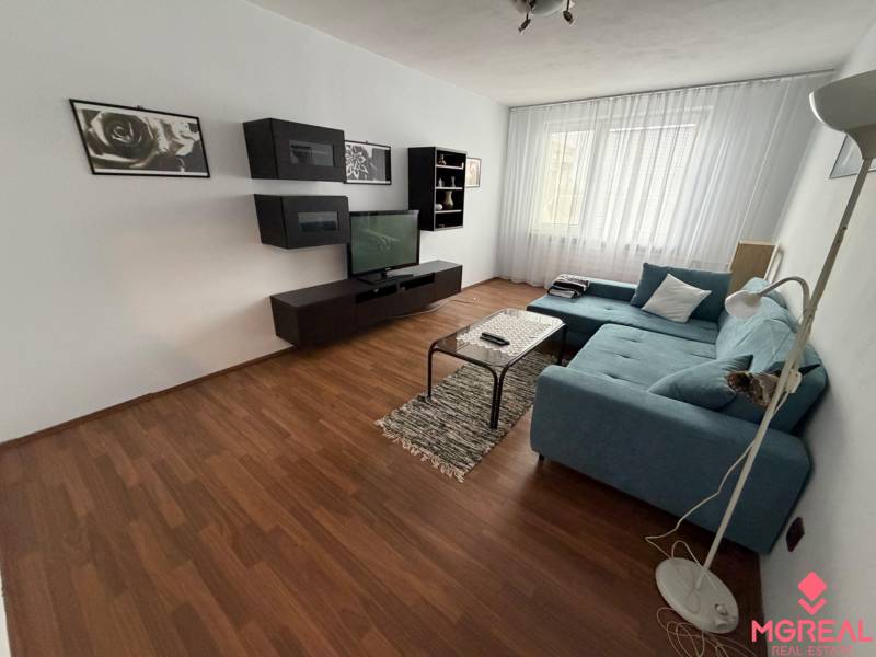 3 izbový byt bez balkóna Topoľčany  - Obývačka s podlahou s dreveným dekorom a sedačkou v 3-izbovom byte.